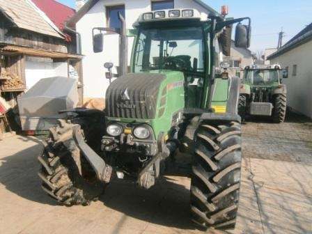 Używany ciągnik rolniczy Fendt 312 Vario widok na przód pojazdu na tle zabudowań gospodarczych 
