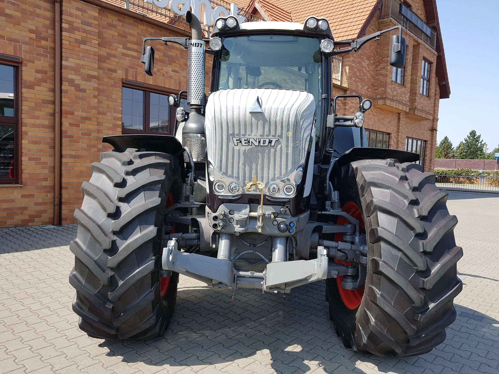 Używany czarny ciagnik Fendt 936 widok z przodu na tle klinkierowego budynku