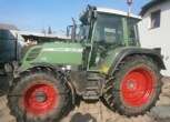 Zadbany używany ciągnik rolniczy Fendt 312 Vario widok na lewy bok pojazdu na tle zabudowań gospodarstwa 